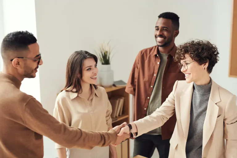 A group of people smiling and shaking hands.