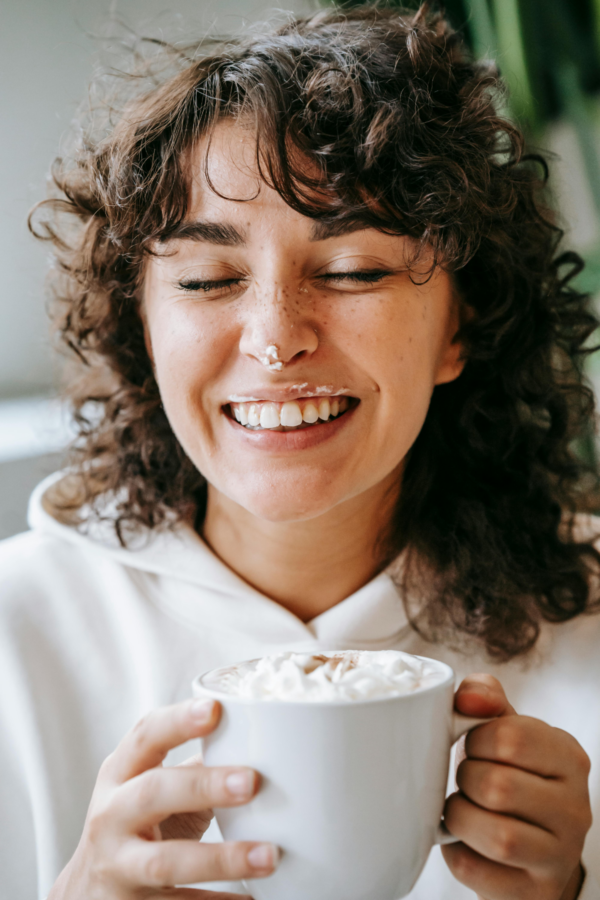 A woman smiling while she enjoys one of her guilty pleasures