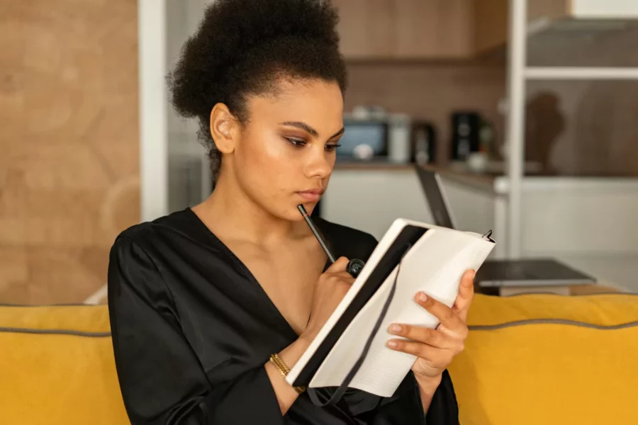 Woman thinking deeply and writing in a notebook